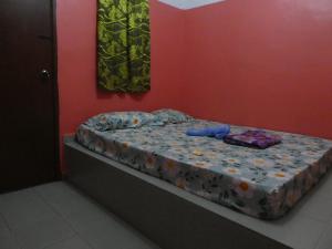 a small bed in a room with a red wall at TIT MOTEL in Sungai Petani