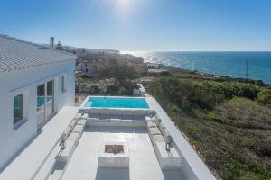 a house with a swimming pool and the ocean at Villa Sublime in Colares