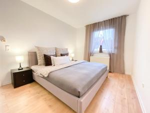 a white bedroom with a large bed and a window at Apartment Mozart in Gernsbach