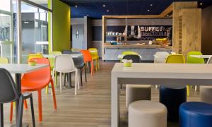 een restaurant met kleurrijke stoelen en tafels in een cafetaria bij ibis budget Saint Malo Centre in Saint-Malo