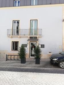 un edificio blanco con dos macetas delante de él en Villa Graça -Hostels and Apartments en Santarém