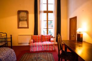 sala de estar con silla roja y mesa en The Riverside Gîte Lagrasse, en Lagrasse