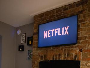 a television on a brick wall with the netflix sign at The Gathering @ Liver House - Hot Tub - Near Liverpool - Sleeps Up To 20 in Rock Ferry