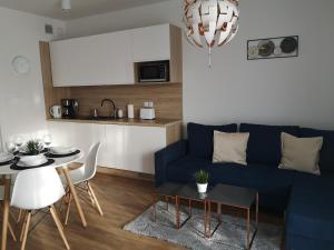 a living room with a blue couch and a table at Apartament Piaskowy Sunset Resort in Grzybowo