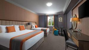 a hotel room with two beds and a desk at Midlands Park Hotel in Portlaoise