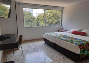 a bedroom with a bed and a large window at Hotel Casa Santa Monica Norte in Cali