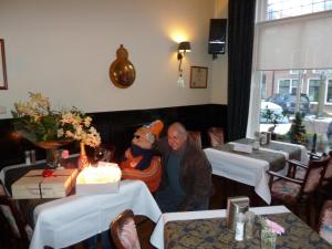 Un uomo piu' vecchio seduto in un ristorante con un uomo in abito da Babbo Natale. di Hotel Centraal a Harlingen