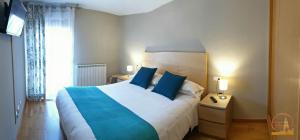 a bedroom with a large bed with blue pillows at EL CAPRICHO DEL BURGO in El Burgo de Osma