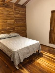 a bedroom with a bed with a wooden wall at Casa de Paz in San Vicente