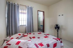 a bedroom with a white bed with red squares on it at Casa com piscina, wifi e churrasqueira em unamar. in Tamoios