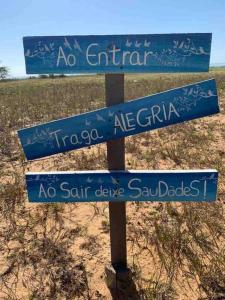three blue signs on a pole in the sand at Casa com piscina, wifi e churrasqueira em unamar. in Tamoios