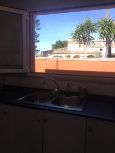 fregadero de cocina y ventana con vistas a un edificio en Casa buganvilla, en Almarda