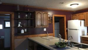 a kitchen with wooden cabinets and a white refrigerator at The Lodge - Chestnut Log Cabin & Game Room in Genoa
