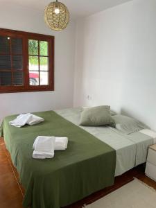 a bedroom with a large green bed with towels on it at Apartamento Can escaragoli in Cala en Porter