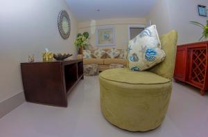 a living room with a yellow chair with a pillow on it at Lantana Barbados Condos in Saint James