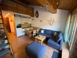 a living room with a blue couch and a kitchen at Penthouse an Skipiste mit Hochkönigcard SKIIN SKIOUT in Maria Alm am Steinernen Meer