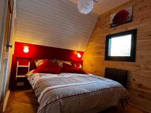 a bedroom with wooden walls and a bed with red pillows at Chalet du Fayard - jacuzzi avec vue et détente en pleine nature in Belfahy