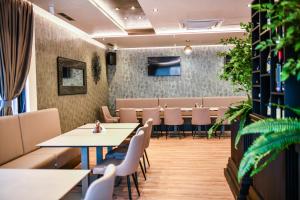 a dining room with tables and chairs and plants at Zlatna Kruna in Banja Luka