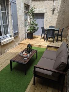 a patio with a couch and a table on grass at Appartement au cœur du centre ville de Blois in Blois