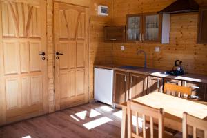 a kitchen with wooden cabinets and a white refrigerator at Domki Letniskowe Kopań in Darłówko