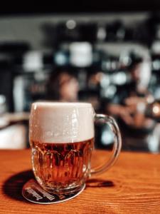 una taza de cerveza de cristal sentada en una mesa en Penzion Na Vošverku en Čelákovice