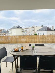 - une table avec des chaises et un ordinateur portable sur la terrasse dans l'établissement F2 Charmant avec Grande Terrasse, à Corbeil-Essonnes