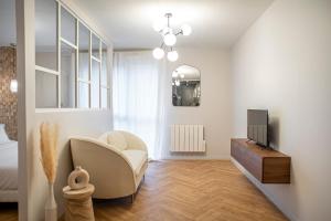 a living room with a chair and a television at Suite Georgia - Check in h24 - Wifi in Villeurbanne