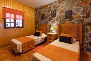 1 Schlafzimmer mit 2 Betten und einer Steinmauer in der Unterkunft Villa Sara Fuerteventura in Cardón + 21 Fotos
