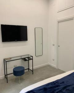 een slaapkamer met een bureau en een tv aan de muur bij Sellaria4 Guest House in Napels