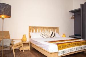 um quarto com uma cama, um candeeiro e uma cadeira em Ndar Ndar House em Saint-Louis