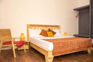 una camera con letto in legno, cuscini e tavolo di Ndar Ndar House a Saint-Louis