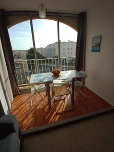a table and chairs in a room with a large window at Studio Cap d'Agde le Môle in Cap d'Agde