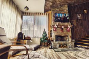 a living room with a christmas tree and a fireplace at Къща За Гости Уют Guest House Cozy in Starosel