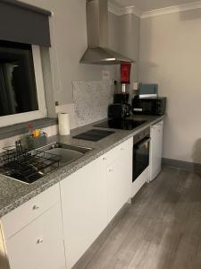 a kitchen with white cabinets and a counter top at Burnside in Oban