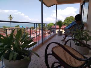 a person sitting on a balcony looking out at the ocean at Cole Street Guesthouse in Freetown