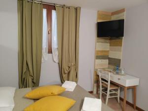 Un dormitorio con una cama con almohadas amarillas y una mesa. en Bed & Breakfast Ca'Bassano en Bassano del Grappa