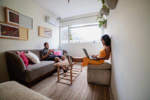 Ein Mann und eine Frau sitzen in einem Wohnzimmer mit einem Laptop in der Unterkunft Selina Punta Del Este in Punta del Este