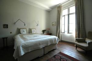 een slaapkamer met een bed, een stoel en een raam bij Château Le Tour - Chambres d'Hôtes in Faux