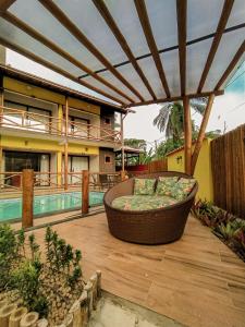 un patio con sofá en una terraza de madera junto a la piscina en Pousada Recanto da Concha, en Itacaré