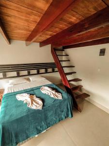 a bed in a room with a wooden staircase at Pousada Recanto da Concha in Itacaré