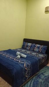 ein Bett mit einer blauen Decke und Kissen darauf in der Unterkunft Al-Kautsar Private Pool WIFI Movies Aircond in Kota Bharu