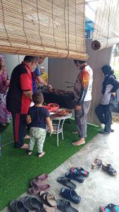 eine Gruppe von Menschen, die um einen Tisch mit einem Kind stehen in der Unterkunft Al-Kautsar Private Pool WIFI Movies Aircond in Kota Bharu