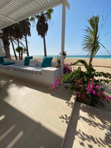 a white couch sitting on the beach with flowers at Villa Nº25b Alfredo Marchetti suites on the beach Praia di Chaves in Cabeçadas