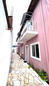 un edificio de color rosa con un balcón en el lateral. en Nossa Casa, Sua Casa 02 - Excelente Localizacao, en Paraty