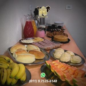 una mesa cubierta con platos de comida y fruta en POUSADA HARAS K&k, en Pinhalzinho