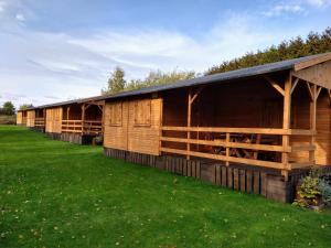 una fila de graneros de madera en un campo de hierba en Dom Wczasowy Pięciu Pomostów I DOMKI LETNISKOWE, en Czaplinek