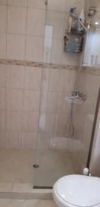 une douche avec une porte en verre à côté des toilettes dans l'établissement Apartment Festival, à Pomorie
