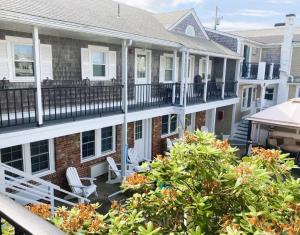 ein Balkon eines Hauses mit zwei weißen Stühlen in der Unterkunft Seashell Motel in Dennis