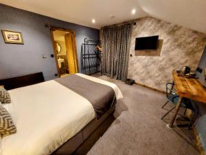 Dormitorio con cama, escritorio y TV en Trawden Arms Community Owned Pub, en Winewall