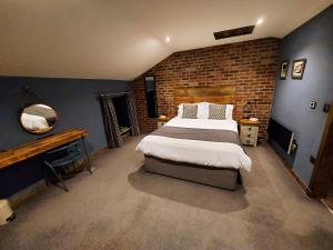 a bedroom with a large bed and a brick wall at Trawden Arms Community Owned Pub in Winewall